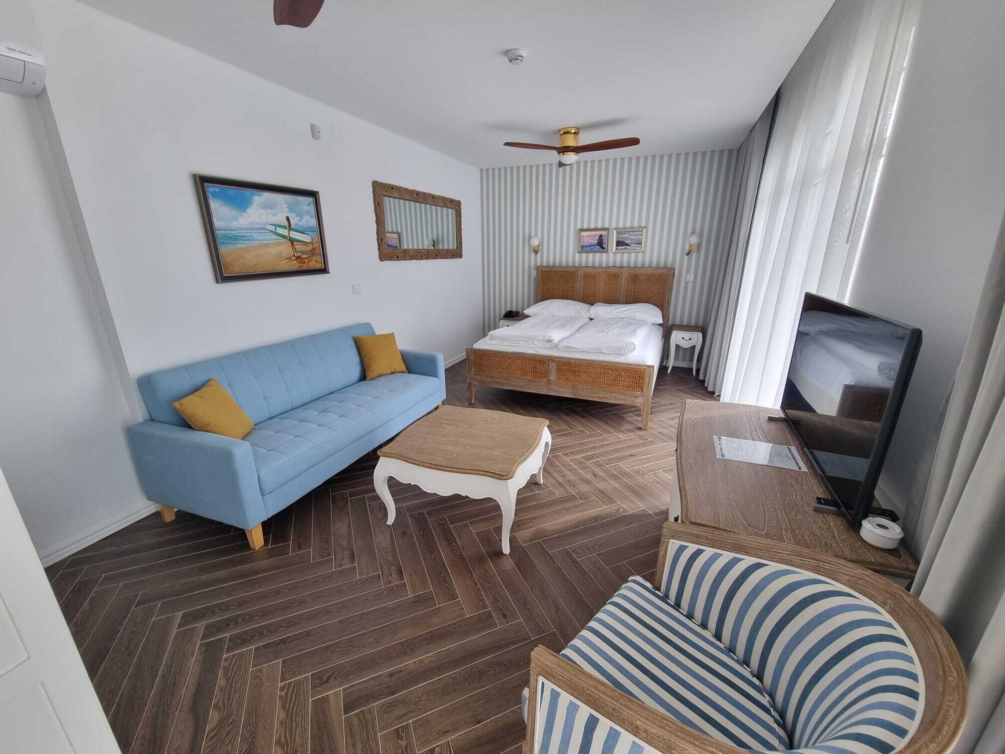 Una habitación de hotel con cama, sofá, televisor y ventilador de techo.