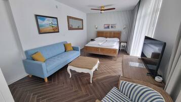 Una habitación de hotel con cama, sofá, televisor y ventilador de techo.