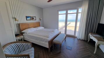 Habitación de hotel con cama, una silla, un escritorio, ventilador de techo y vista a la playa.