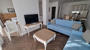 Una sala de estar moderna con televisor, sofá y mesa de centro.