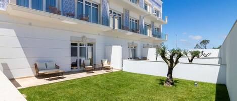 A modern building with a white exterior, multiple balconies, and a well-maintained lawn.