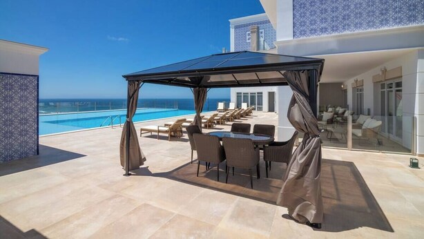 A rooftop terrace with a pool, lounge chairs, and a covered dining area with a view of the ocean. - Ocean View Apartments - Ocean View (Lourinha)