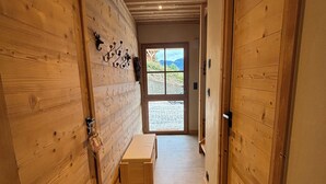 A wooden hallway with a bench, a door with a window, and a wall-mounted decoration. - New luxury chalet in Morzine's La Cote d'Arbroz with a Jacuzzi, beautiful views, and a quiet setting (La Côte-d'Arbroz)