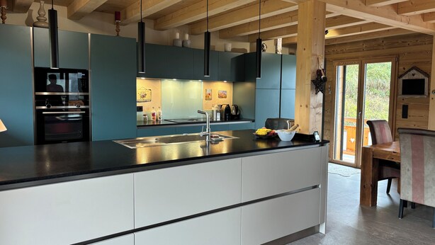 A modern kitchen with a large island, built-in appliances, and a wooden ceiling. - New luxury chalet in Morzine's La Cote d'Arbroz with a Jacuzzi, beautiful views, and a quiet setting (La Côte-d'Arbroz)