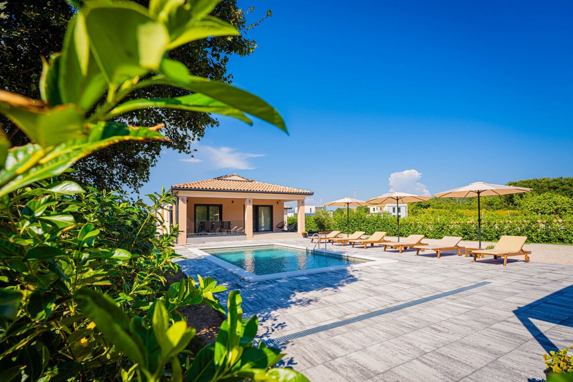 A pool area with lounge chairs and a building with a tiled roof.