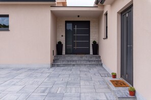 A modern building entrance with a black door, stone steps, and potted plants. - Villa Ardanela in Kapelica  - Haus für 6 Personen (Labin)