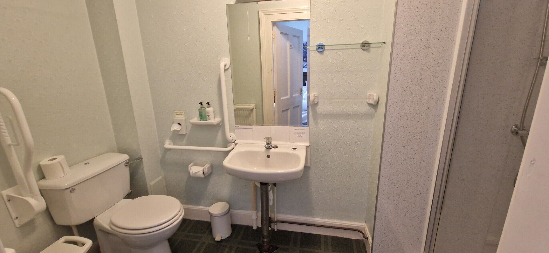A small bathroom with a toilet, sink, and mirror.