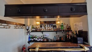 A bar area with shelves of liquor bottles and a wooden bar counter. - Corsewall Lighthouse Hotel (Stranraer)