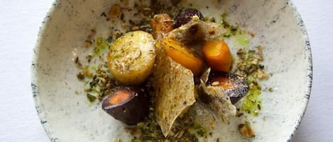 A bowl of food with various vegetables and herbs.
