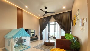 A modern living room with a play tent, a yellow bean bag, a ceiling fan, and a large window. - Paradigm Residence By Antlerzone (Johor Bahru)