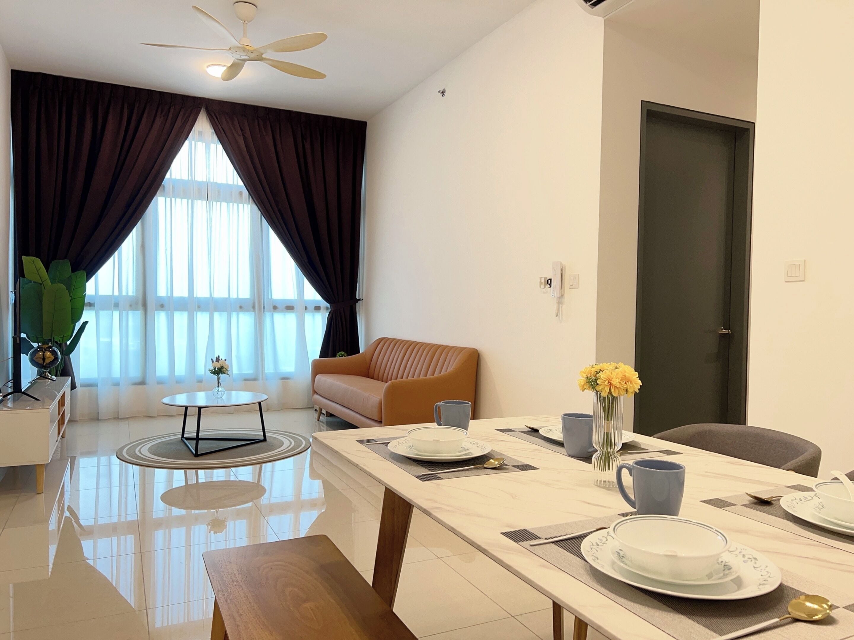 A modern living room with a sofa, a dining table set with plates and cups, a coffee table, and a ceiling fan.