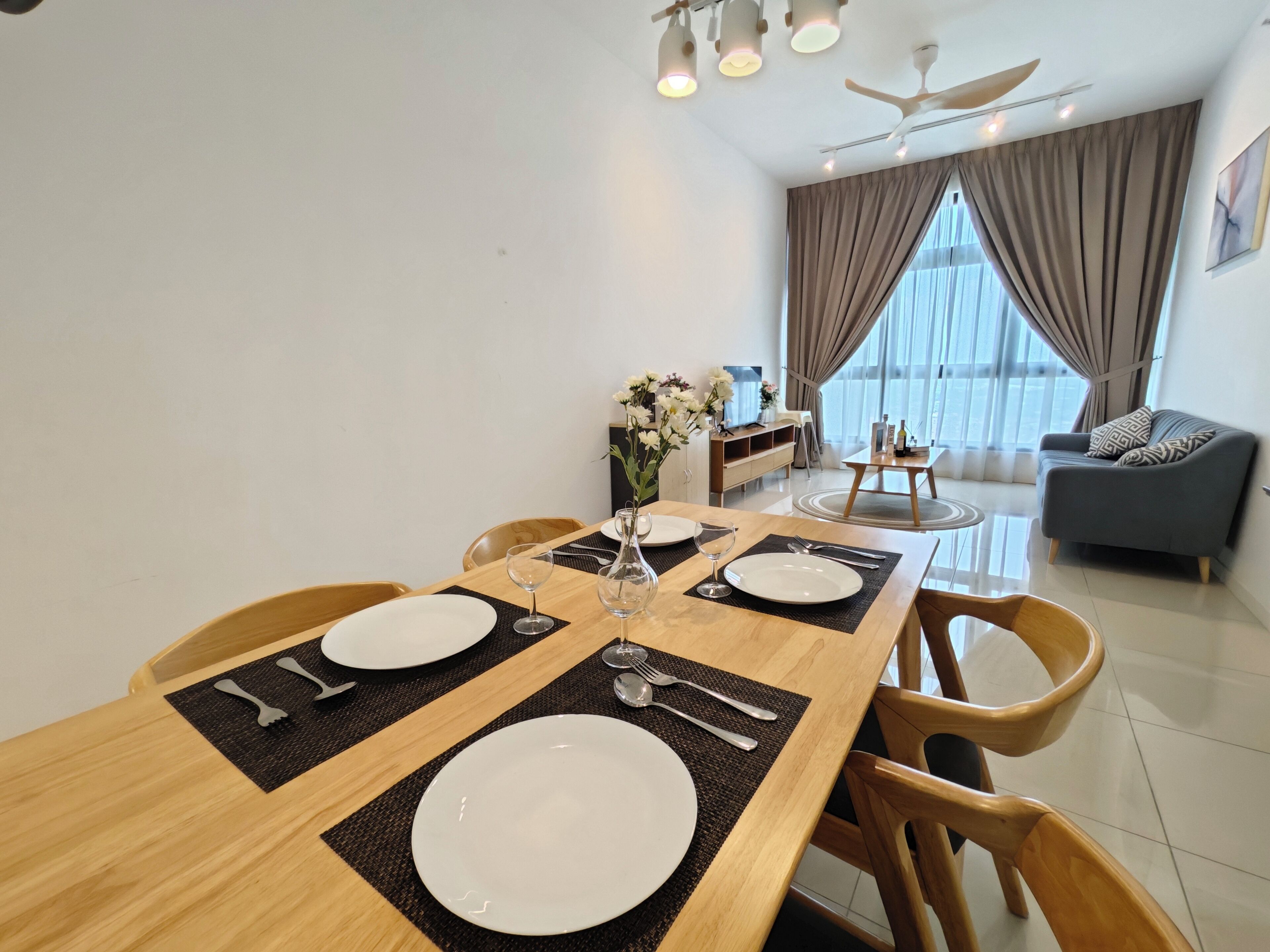 A dining area with a wooden table set for four, including plates, cutlery, and a vase with flowers.