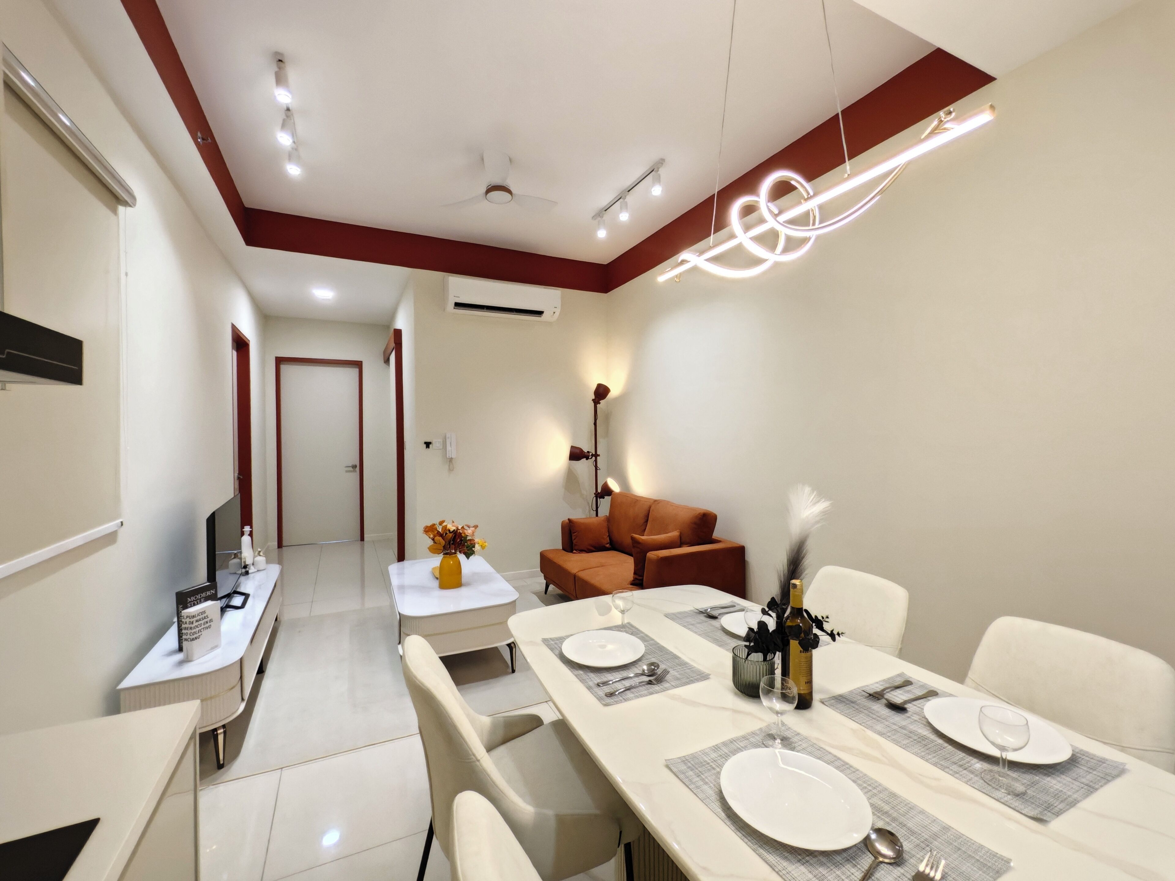 A modern dining area with a long table set for six, a sofa, and a TV on a stand.