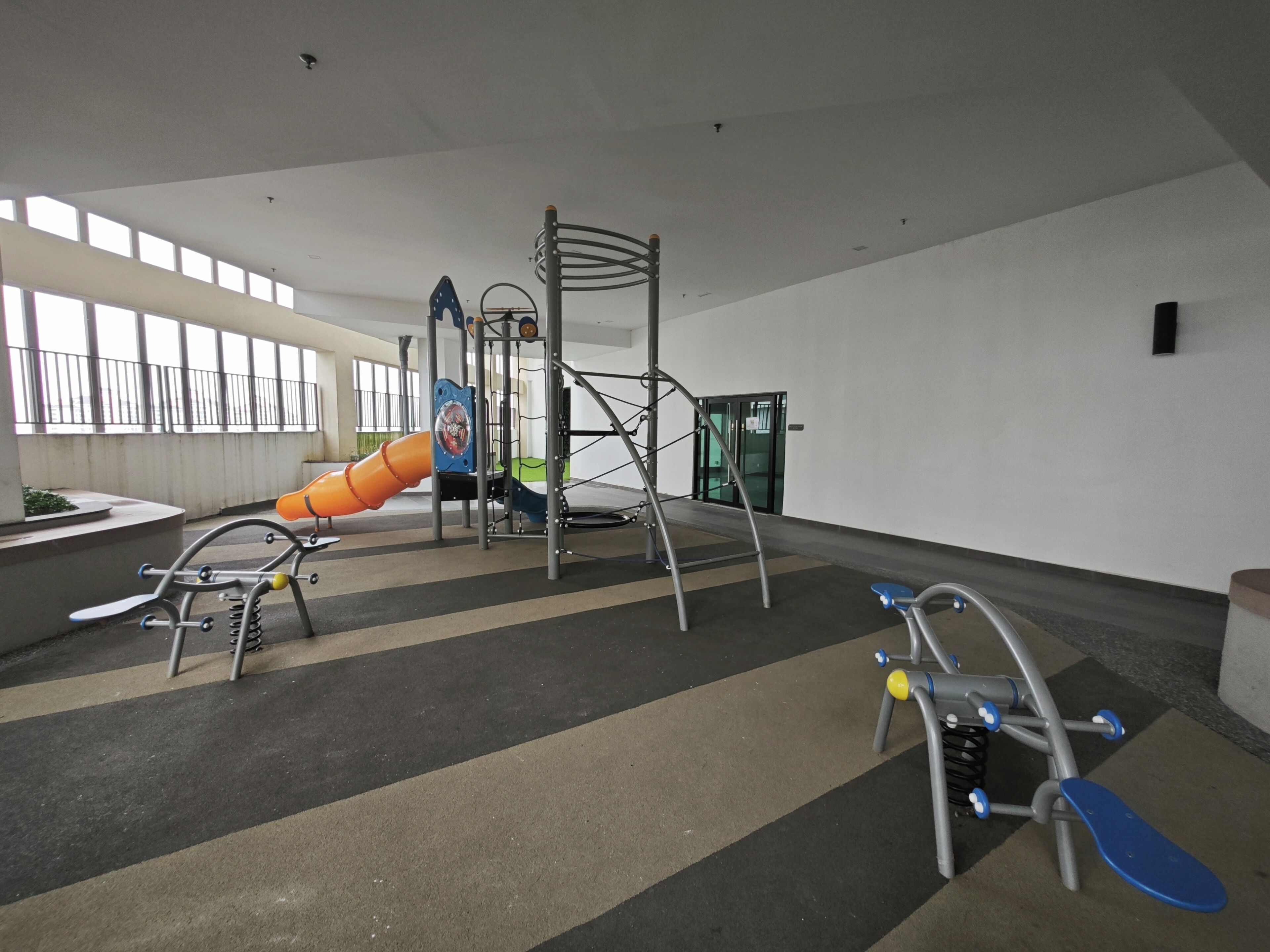 An indoor play area with a slide, climbing structures, and a swing set.