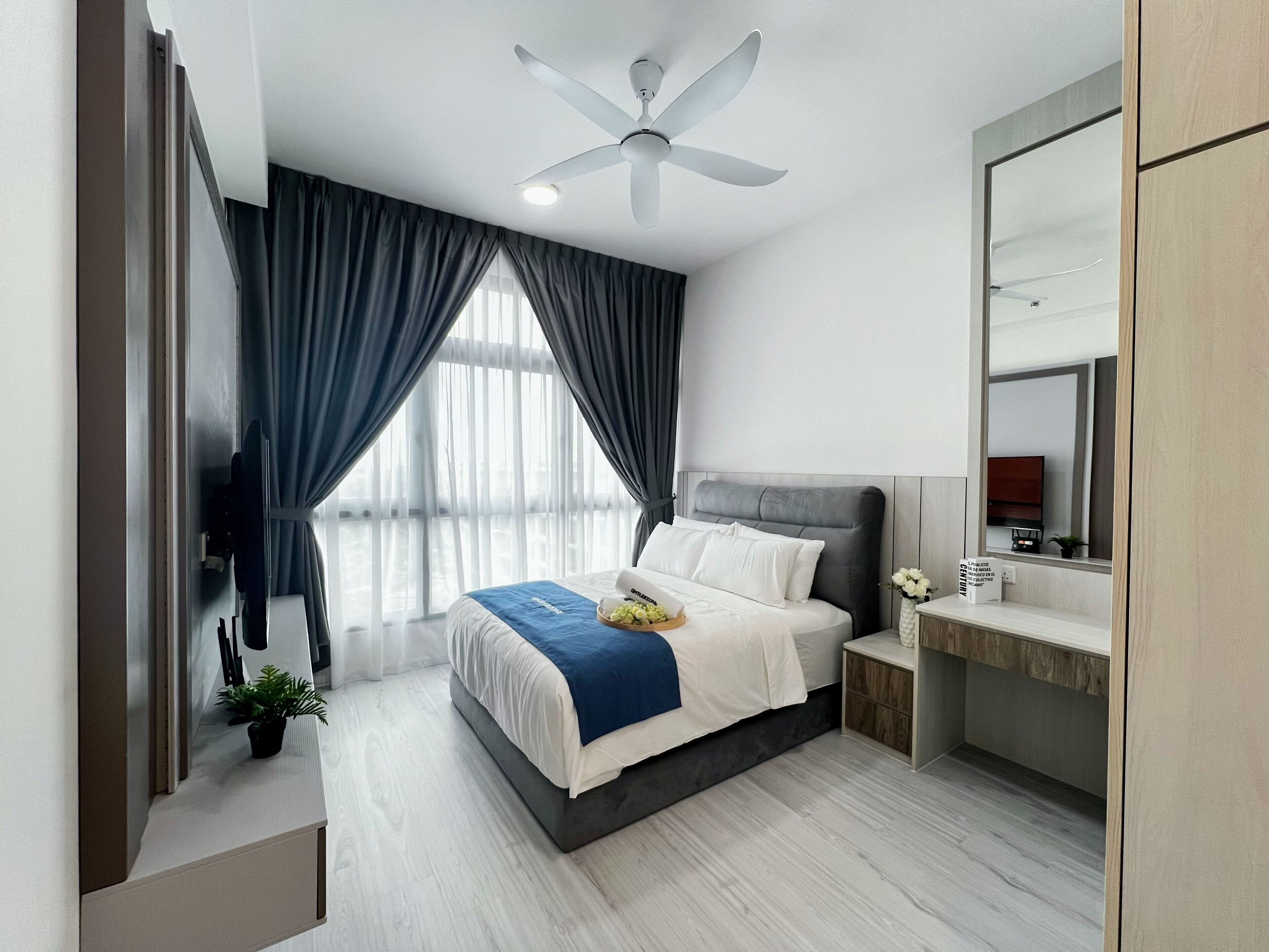 Una habitación de hotel moderna con cama, mesita de noche, espejo, ventilador de techo y ventana con cortinas.