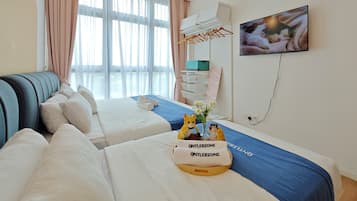 Habitación de hotel con dos camas, televisión, ventilador de techo y ventana con cortinas.