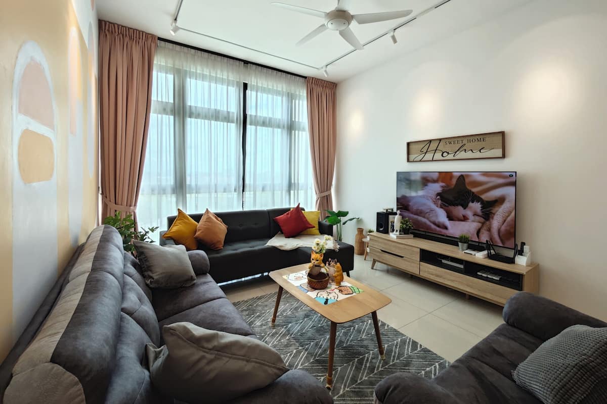 Ein modernes Wohnzimmer mit einem grauen Sofa, einem Holztisch und einem Fernseher auf einem Holzgestell.