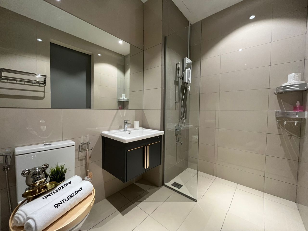 Un baño moderno con cabina de ducha de vidrio, un lavabo blanco y un mueble de tocador negro.