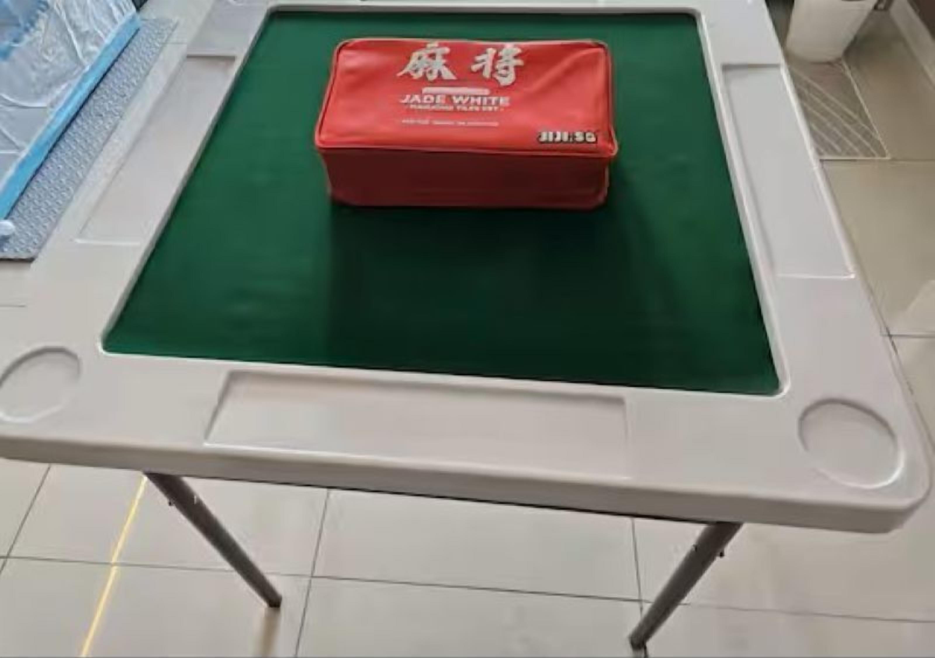 Una mesa con superficie de fieltro verde y un cojín rojo con la etiqueta 'JADE WHITE'.