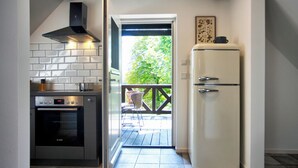 A kitchen with a Bosch oven, a white refrigerator, and a view of a balcony with outdoor furniture.