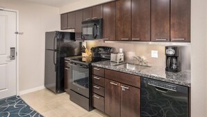 A modern kitchen with dark wood cabinets, stainless steel appliances, and a granite countertop.