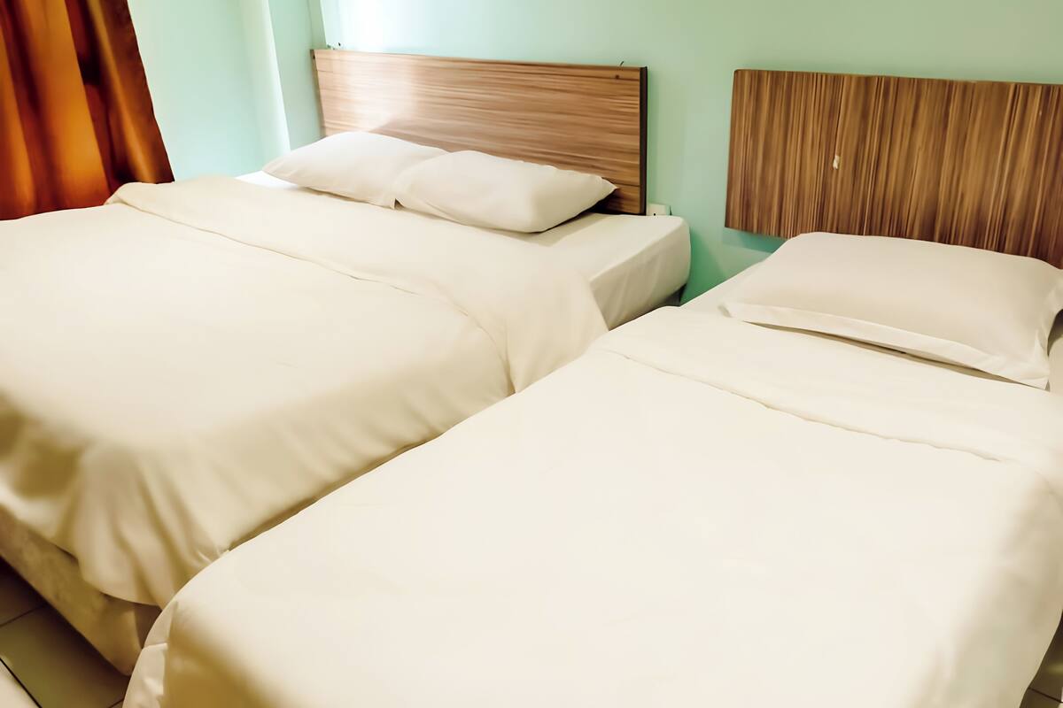 Zwei Einzelbetten mit hölzernen Kopfteilen in einem Zimmer mit hellgrünen Wänden.