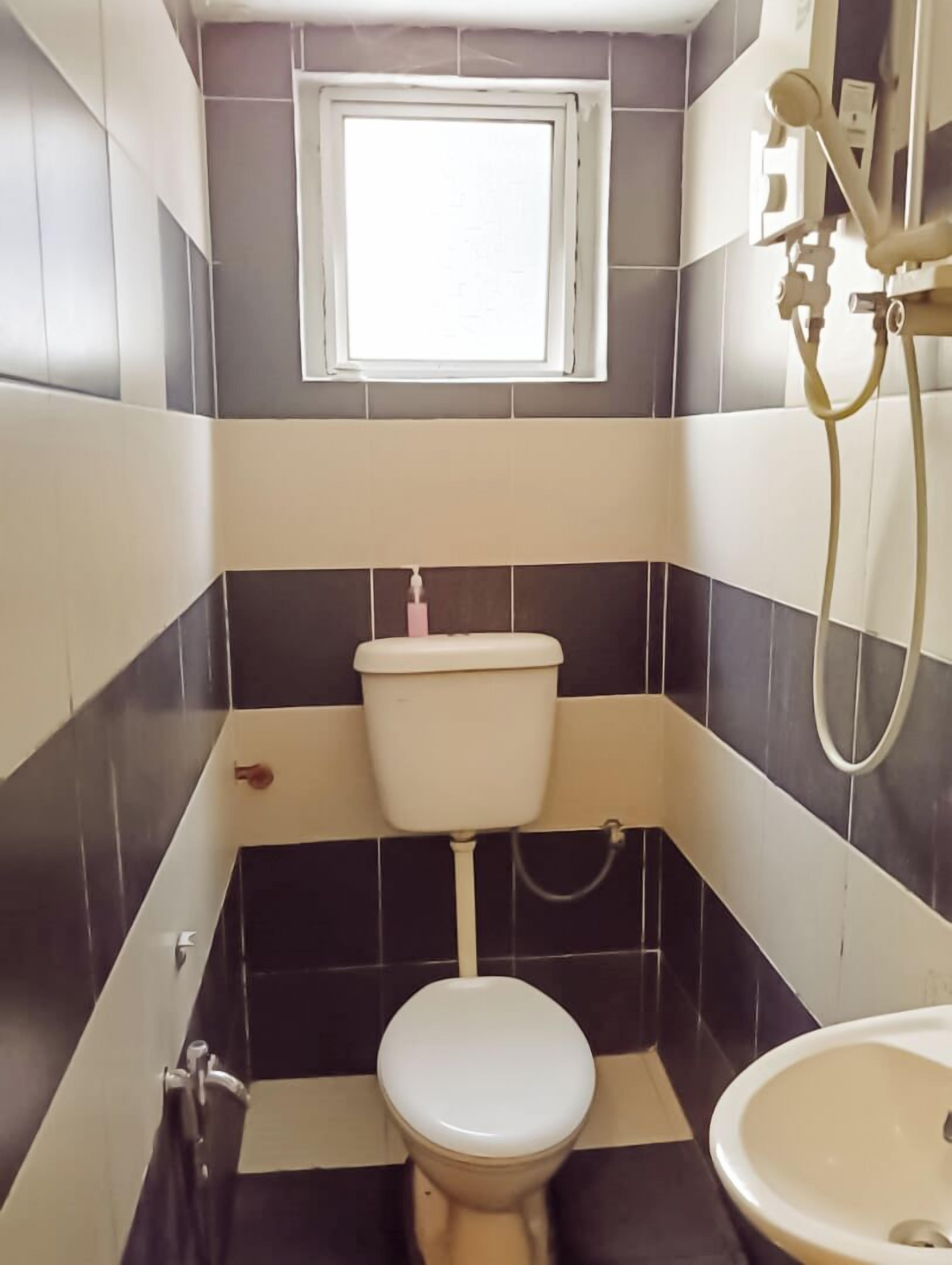 Une petite salle de bain avec des toilettes, un lavabo et une fenêtre située au-dessus des toilettes.