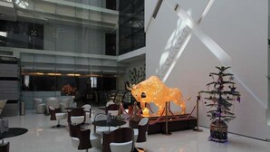 Un espacio interior moderno con fachada de vidrio, una escultura de toro y un árbol de Navidad decorado.