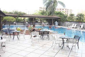 A poolside area with multiple tables and chairs, a covered seating area, and a pool. - Hotel The Cox Today (Cox's Bazar)