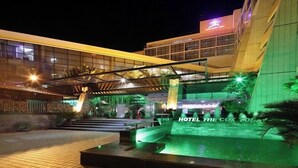 Exterior de un hotel de noche con zona de piscina, un paseo techado y un cartel que dice "HOTEL THE COX FOLLA".