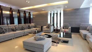 Una sala de estar moderna con un sofá seccional, una mesa de centro y un área de estar con sillones.