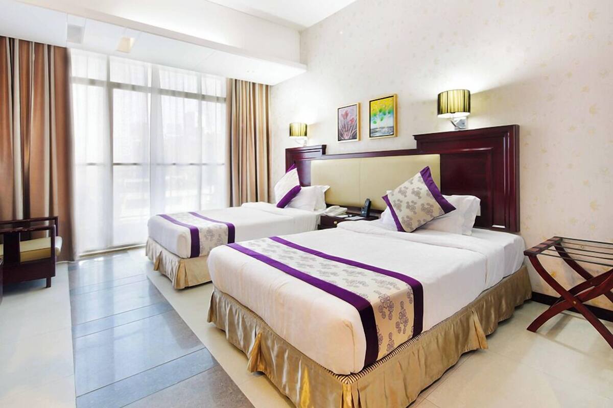 A hotel room with two beds, a desk, and a chair.