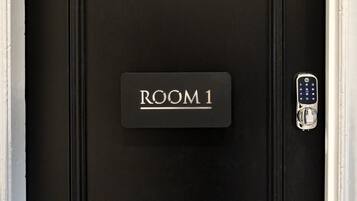A black door with a "ROOM 1" sign and a keypad lock.