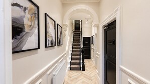 A hallway with a staircase, framed artwork on the walls, and a radiator. - Home at 42 Arkles Lane (Liverpool)