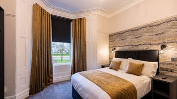A bedroom with a large bed, a stone accent wall, and a view of the outdoors.
