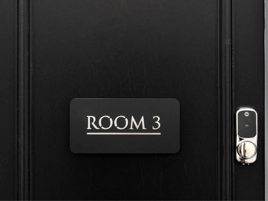 Une porte noire avec une étiquette indiquant « SALLE 3 » et une serrure à clé.