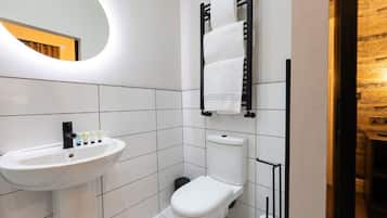Une salle de bain moderne avec un lavabo, des toilettes et un porte-serviettes, le tout de couleur blanche.