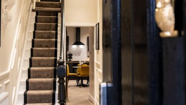A staircase leading to a dining area with a modern kitchen in the background. - Home at 42 Arkles Lane (Liverpool)