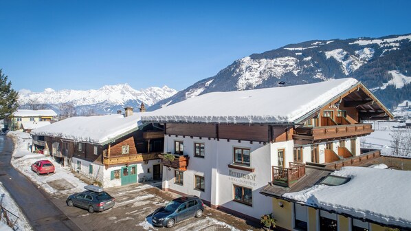 Un chalet traditionnel en bois, avec un toit enneigé, un balcon et une enseigne indiquant qu’il s’agit d’un sauna et d’un centre de bien-être.