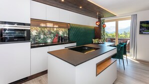 Una cocina moderna con armarios blancos, una isla integrada y vistas a montañas a través de amplios ventanales.
