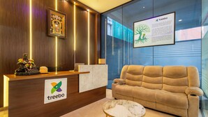 A reception area with a wooden reception desk, a sofa, a small table, and a framed picture on the wall. - Treebo Living Tree opposite Khairatabad Metro (Hyderabad)