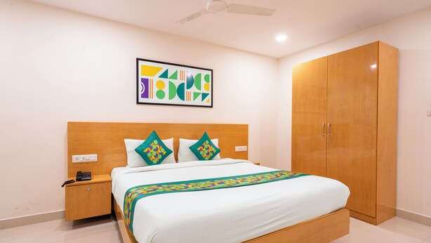 A bedroom with a bed, nightstand, wardrobe, ceiling fan, and abstract artwork on the wall. - Treebo Living Tree opposite Khairatabad Metro (Hyderabad)