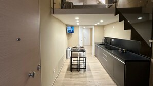 Eine moderne Küche mit Essbereich, einer Treppe und einem Fernseher an der Wand.