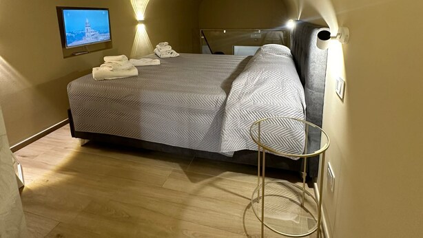 Ein gemütliches Schlafzimmer mit einem Bett, einem Fernseher und einer Lampe.