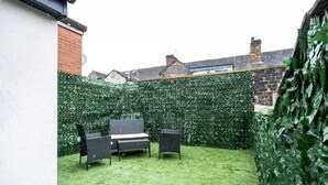 A backyard with a green hedge, a bench, and two chairs. - COSY CRUISE CRIBS - MODERN HOME FROM HOME - CENTRAL LOCATION. (Stoke-on-Trent)