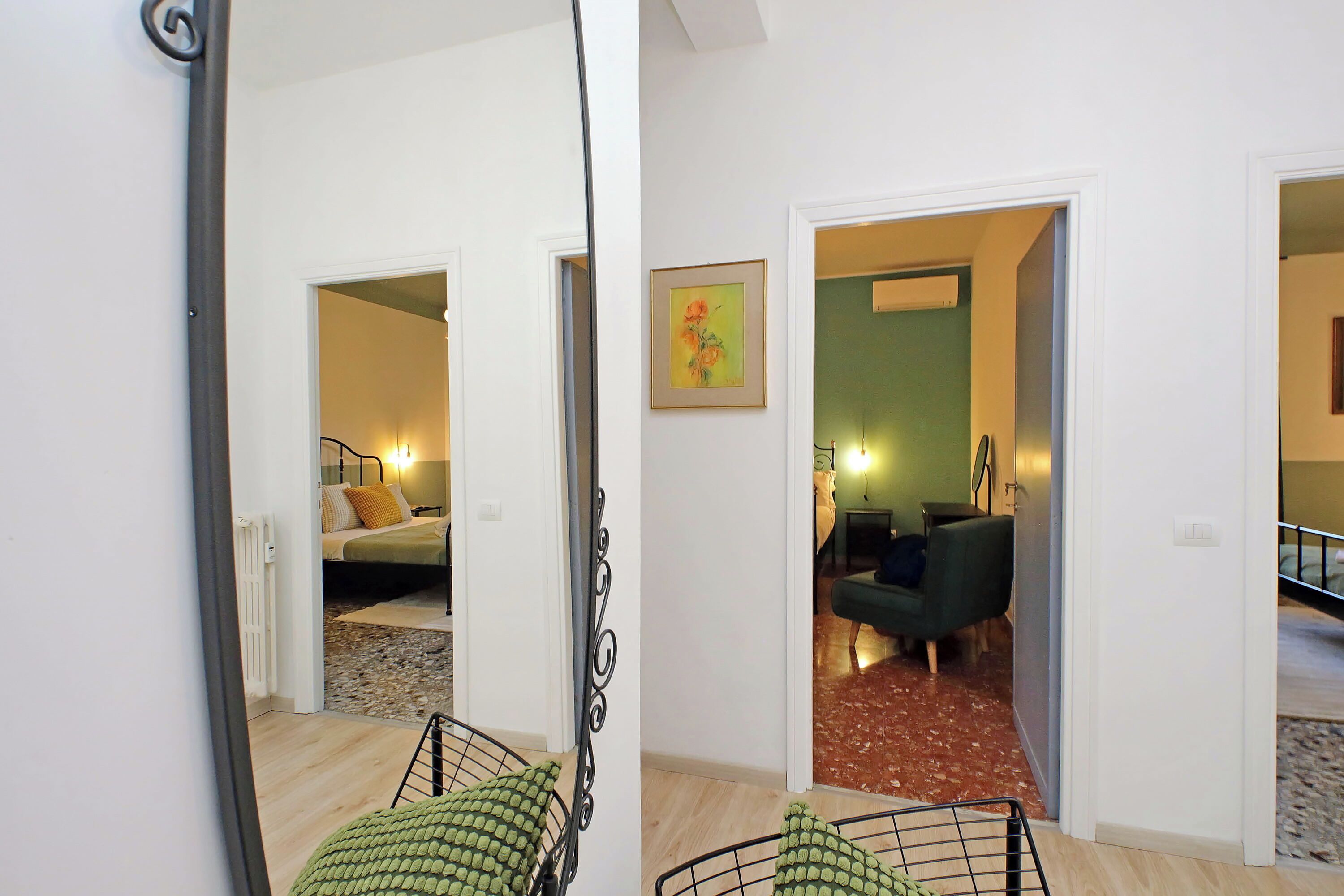 A hallway with a bed, a green sofa, and a framed picture on the wall.