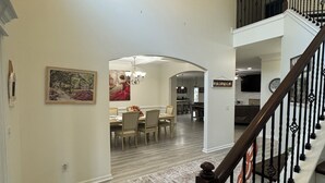 A spacious interior with a staircase, dining area, and kitchen visible. - Spacious 5-bedroom house in peaceful Midway with WiFi, AC Close to Savannah GA  (Midway)