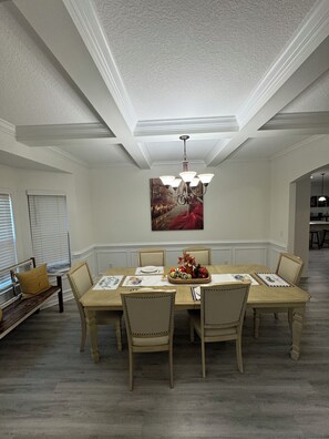 A dining room with a large table, six chairs, a chandelier, and a painting on the wall. - Spacious 5-bedroom house in peaceful Midway with WiFi, AC Close to Savannah GA (Midway)