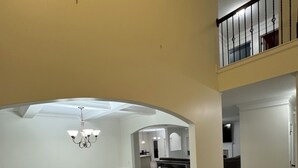 A spacious interior with a high ceiling, a chandelier, and a dining area with a kitchen in the background. - Spacious 5-bedroom house in peaceful Midway with WiFi, AC Close to Savannah GA  (Midway)