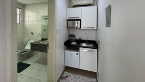 Un angolo cottura compatto con mobili bianchi, un forno a microonde e un lavandino.